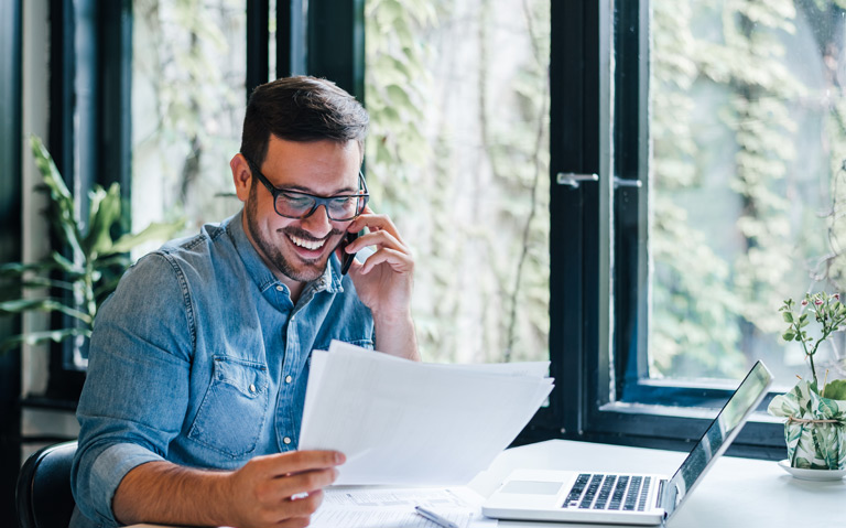 An employee looking at documents while talking on the phone